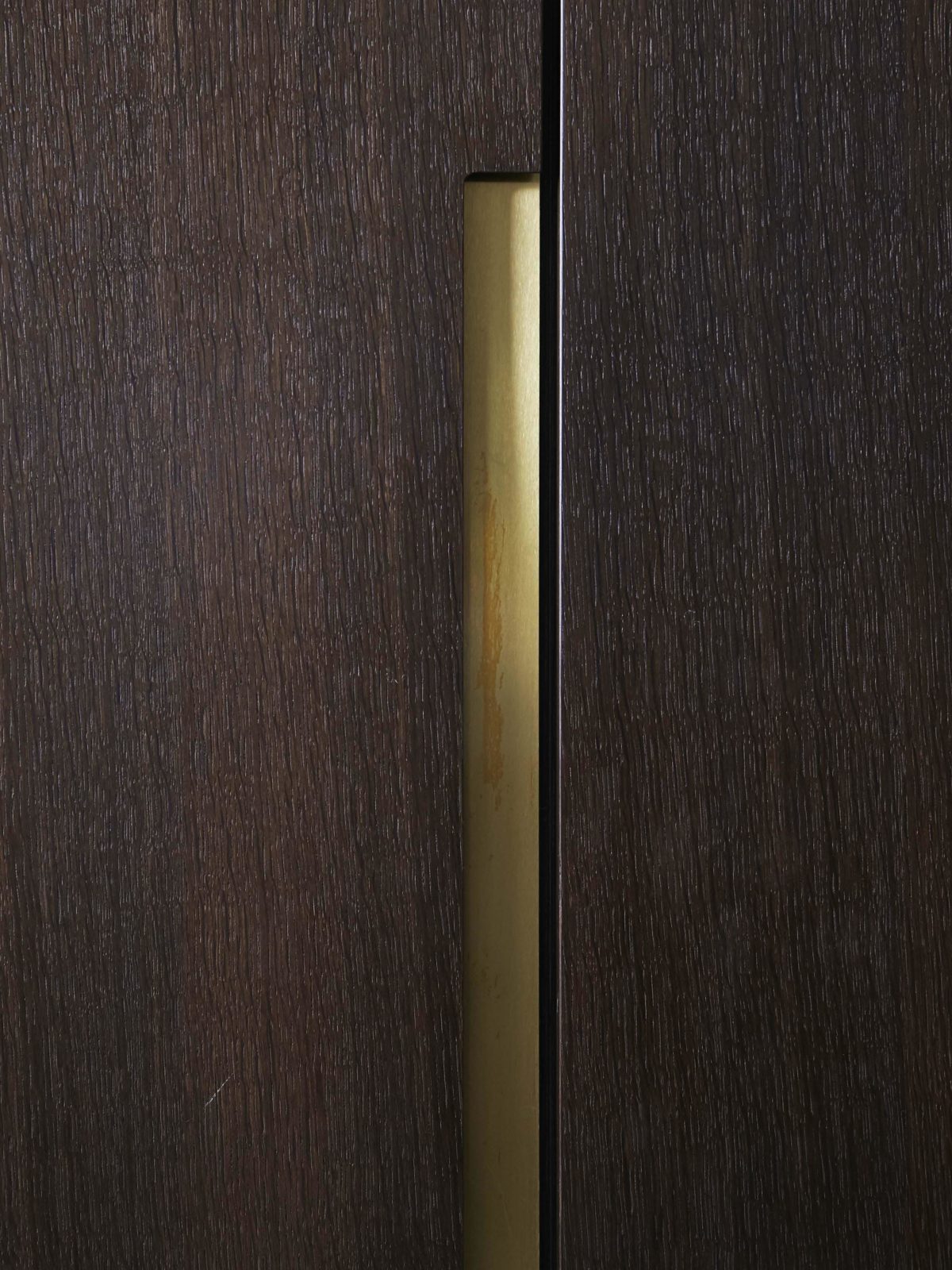 Fumed oak handleless wardrobe with satin brass detail