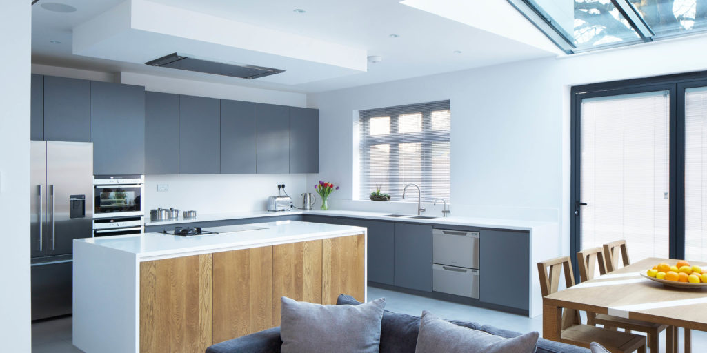 Open plan kitchen with matt grey lacquered doors, Antartica Corian worktop and splashback, solid oak island doors