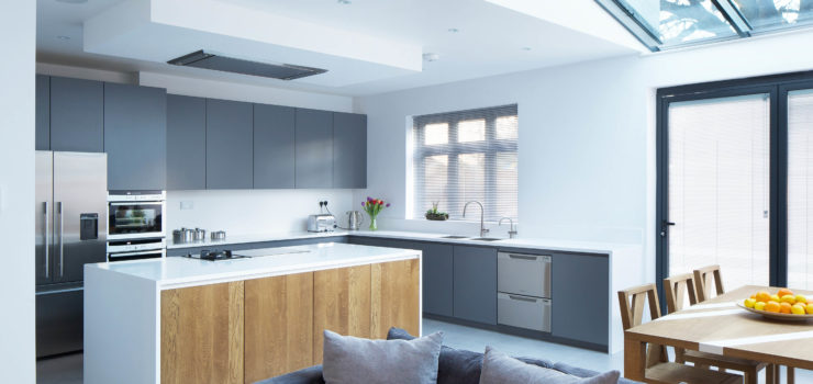 Open plan kitchen with matt grey lacquered doors, Antartica Corian worktop and splashback, solid oak island doors